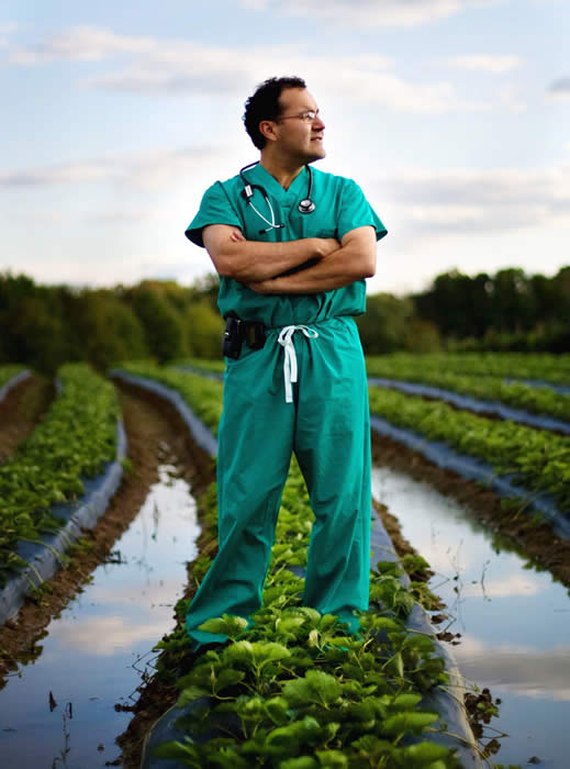 Dr. Alfredo Quinones-Hinojosa standing in a row of farmland.