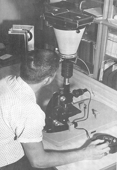 Student taking a photo of a microscopic image, 1963